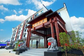 Entrada de hotel con elementos arquitectónicos tradicionales, incluyendo un tejado rojo y estatuas de leones de piedra.