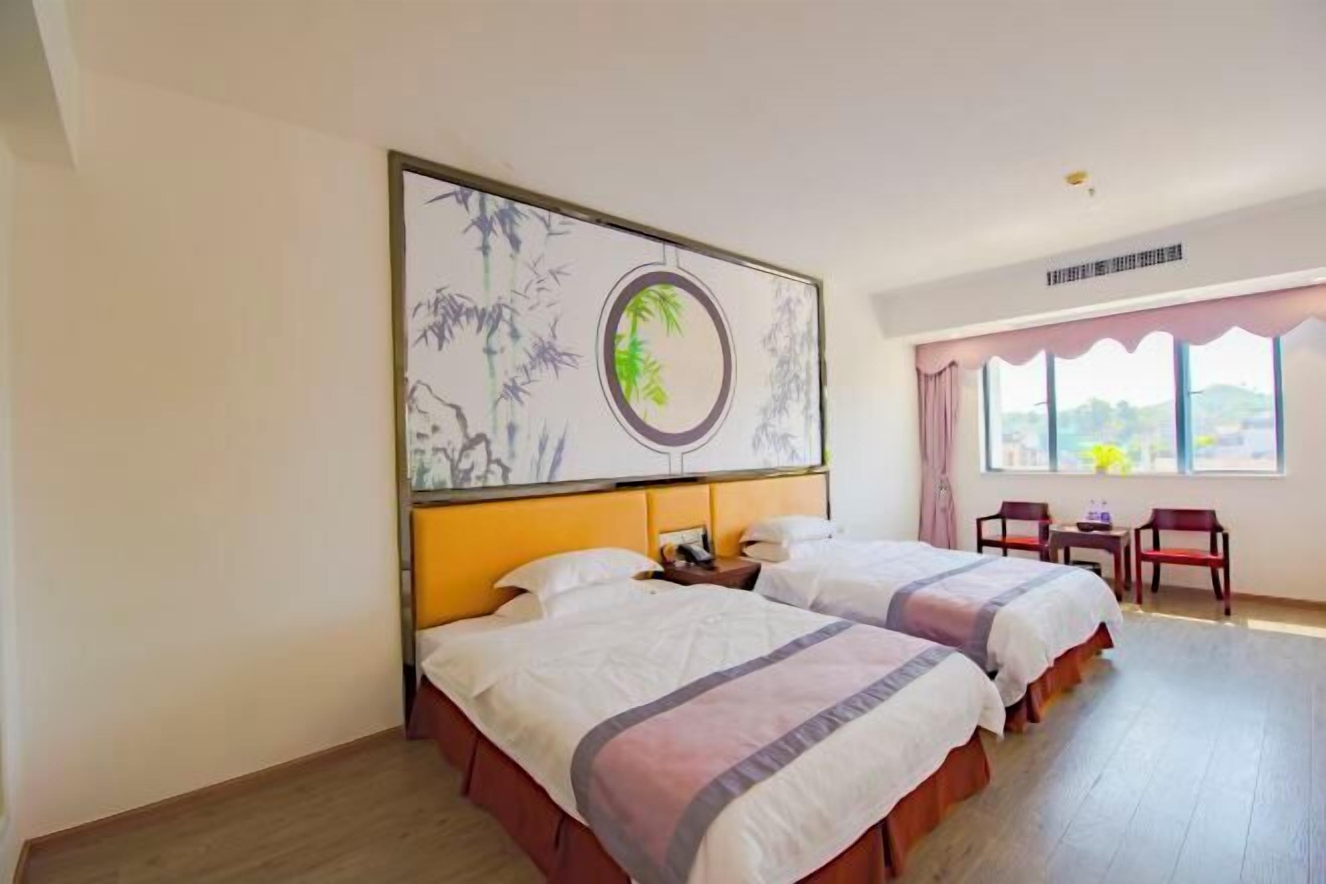 A hotel room with two beds, a large artwork on the wall, a window with curtains, and a small table with chairs.