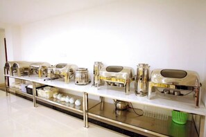 Montaje de bufé con diferentes equipos de servicio de alimentos en una mesa larga.