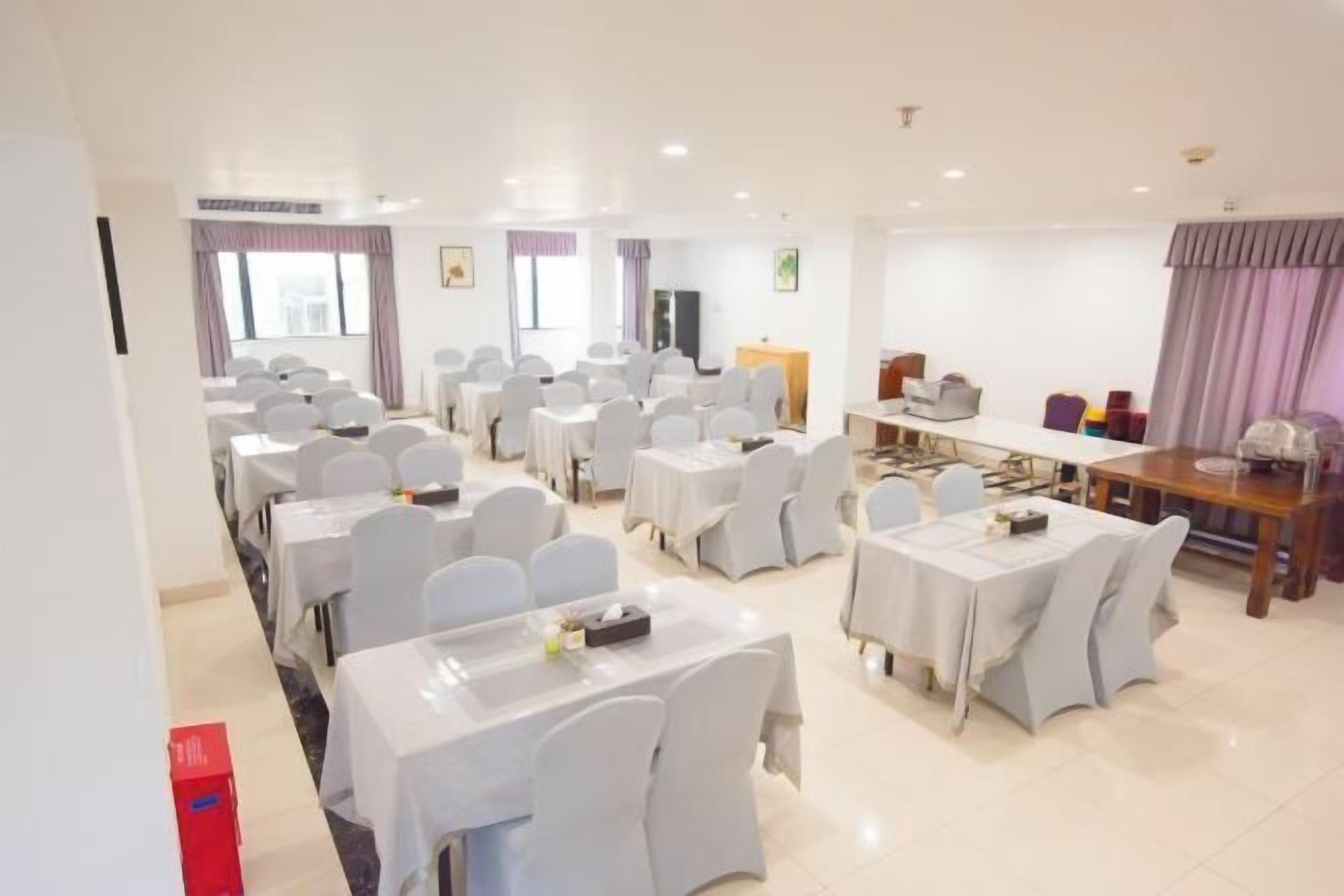 A conference room with multiple tables and chairs, a podium, and a large screen.