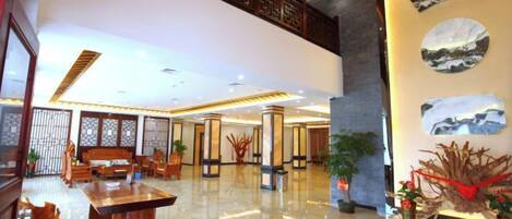 A spacious lobby with a reception desk, seating area, and decorative plants.