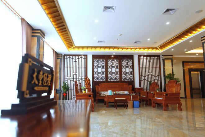 A hotel lobby with a reception desk, seating area, and decorative screens.