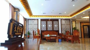 A hotel lobby with a reception desk, seating area, and decorative screens.