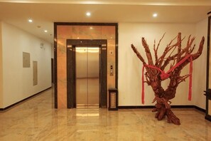 An elevator, a reception area, and a sculpture. - Tongjing Hotel (Renhua)