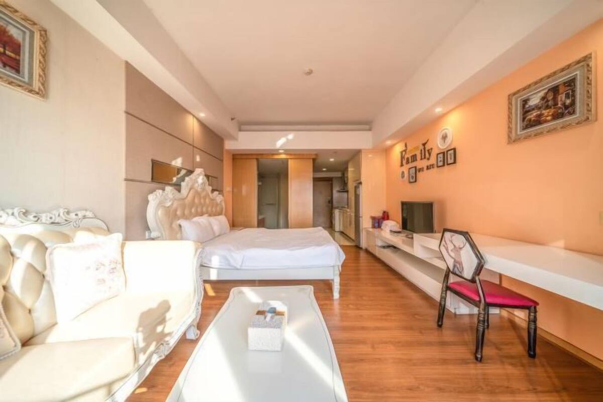 Et moderne hotelværelse med seng, sofa, sofabord og fjernsyn.
