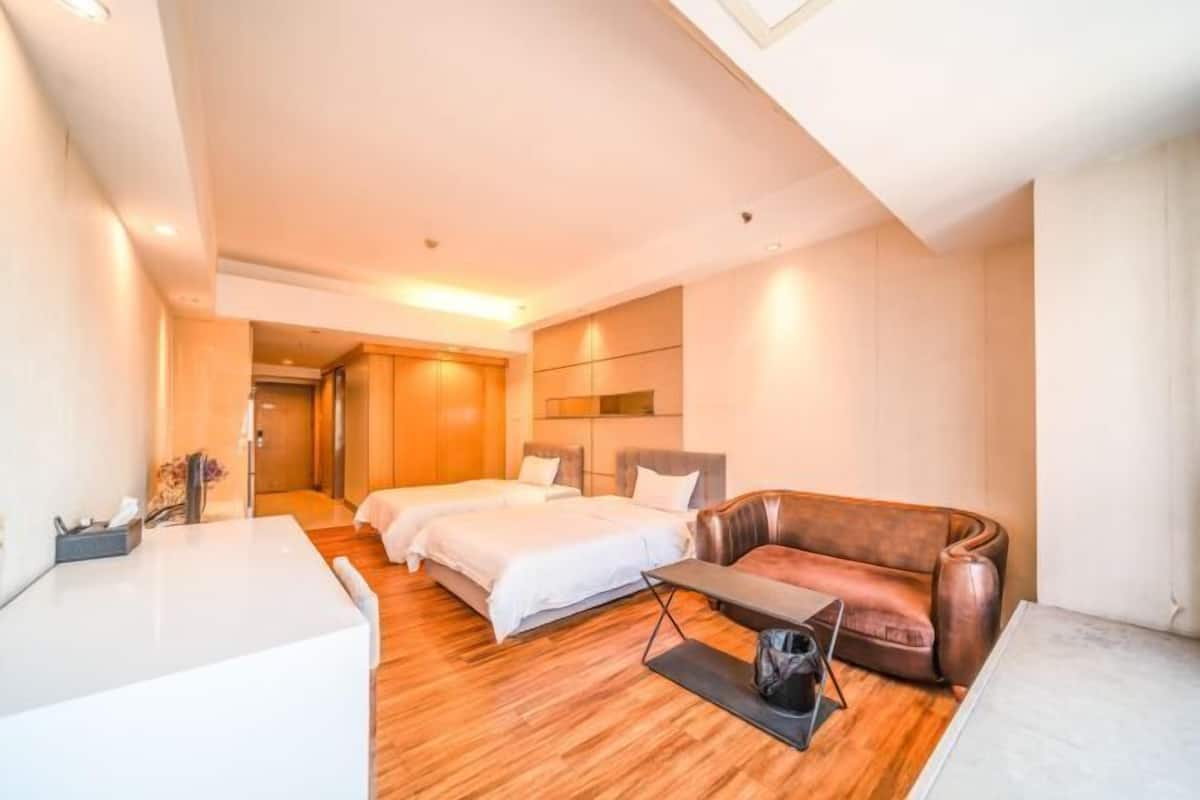 Et hotelværelse med seng, sofa, skrivebord og et spejl.
