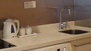 Una cocina con un lavamanos, un hervidor y una cafetera.