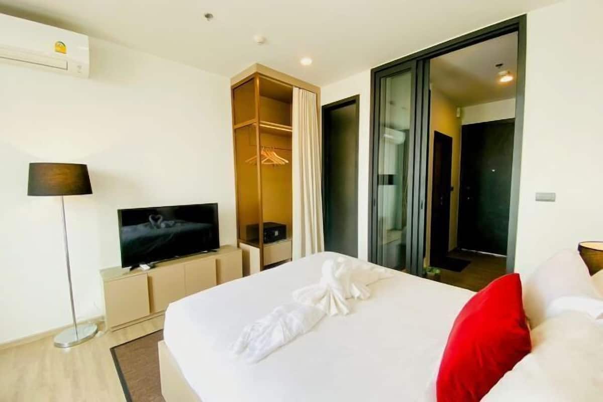A hotel room with a bed, a TV, a wardrobe, and a sliding door leading to a bathroom.