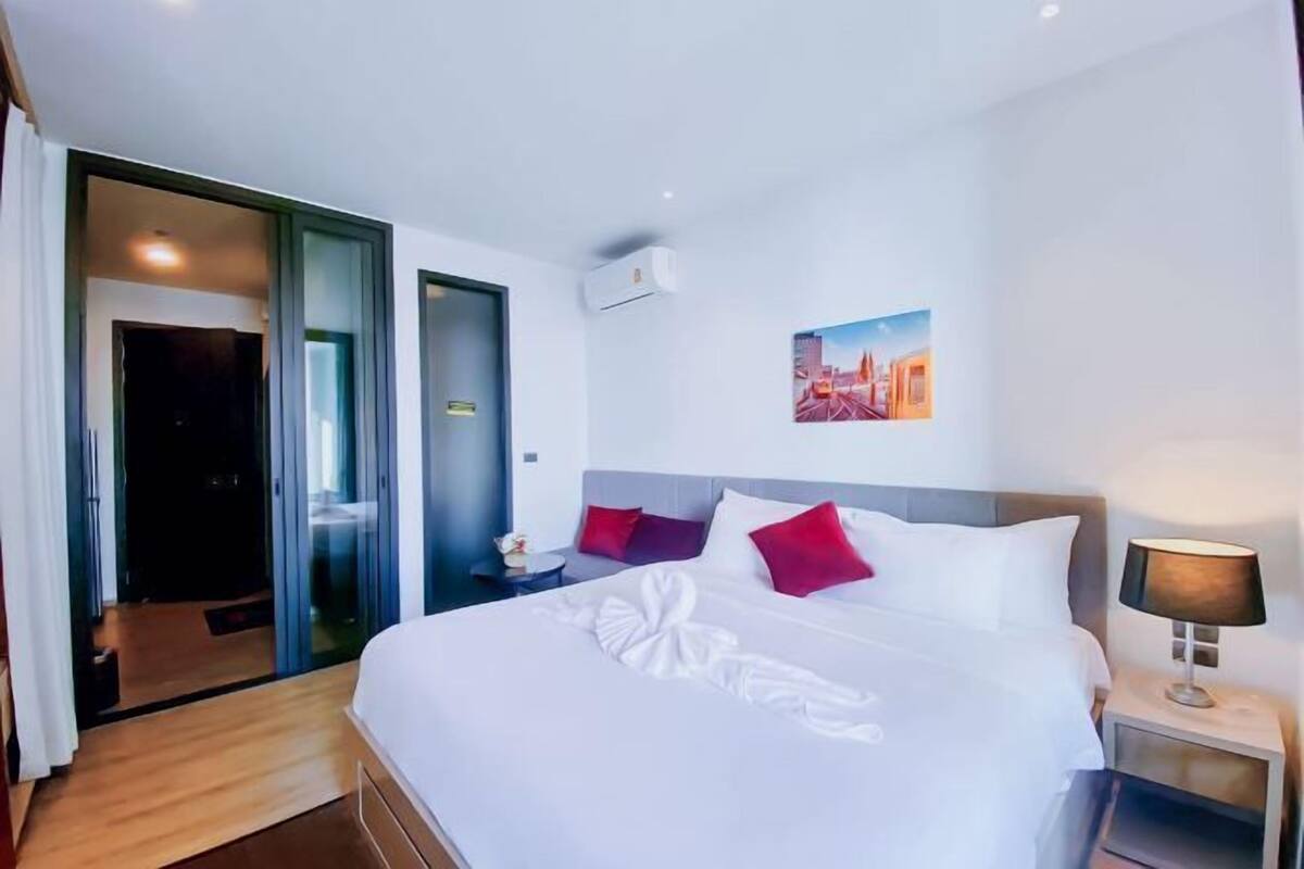 A hotel room with a large bed, a nightstand, a lamp, and a painting on the wall.