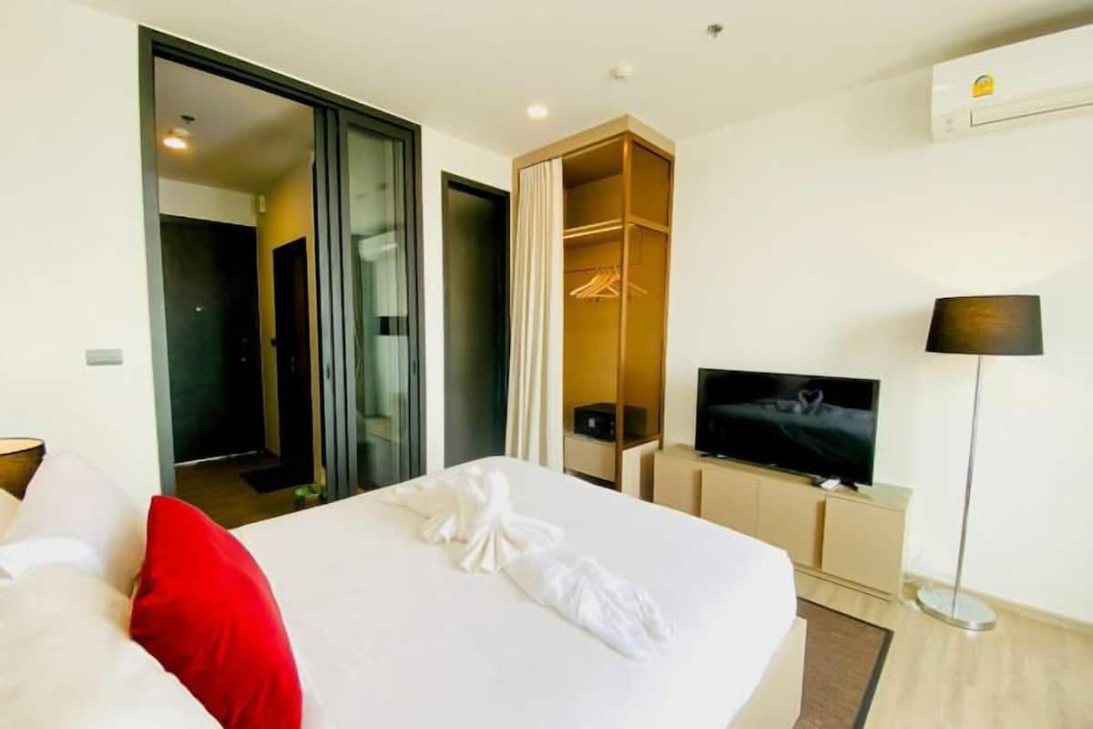 A hotel room with a bed, a TV, a wardrobe, and a mirror.