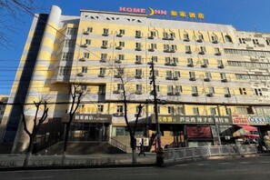 A multi-story hotel with a prominent 'HOME Inn' sign, multiple balconies, and a storefront with various businesses.