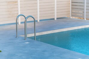 Ein Schwimmbecken mit Metallgeländern und einer gefliesten Liegefläche.