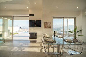 A modern dining area with a glass table and chairs, a fireplace, and a view of the outdoors. - Fantasea Villas, villa Lux (Sternes)