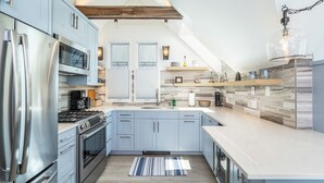 A modern kitchen with stainless steel appliances, light blue cabinets, and a large island.