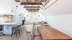 A modern kitchen with a central island, bar stools, and a wooden dining table.