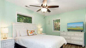 A bedroom with a bed, nightstands, a dresser, a ceiling fan, and a TV on a dresser. - Beach Bunker | Cozy 2BR Soundside Cottage w/ Screened Porch & Fenced Yard (Emerald Isle)