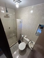 Un baño con inodoro, bidé y ducha con mampara de vidrio.