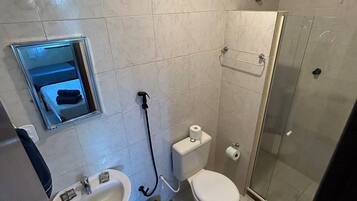 Un baño con lavamanos, inodoro y ducha con mampara de vidrio.