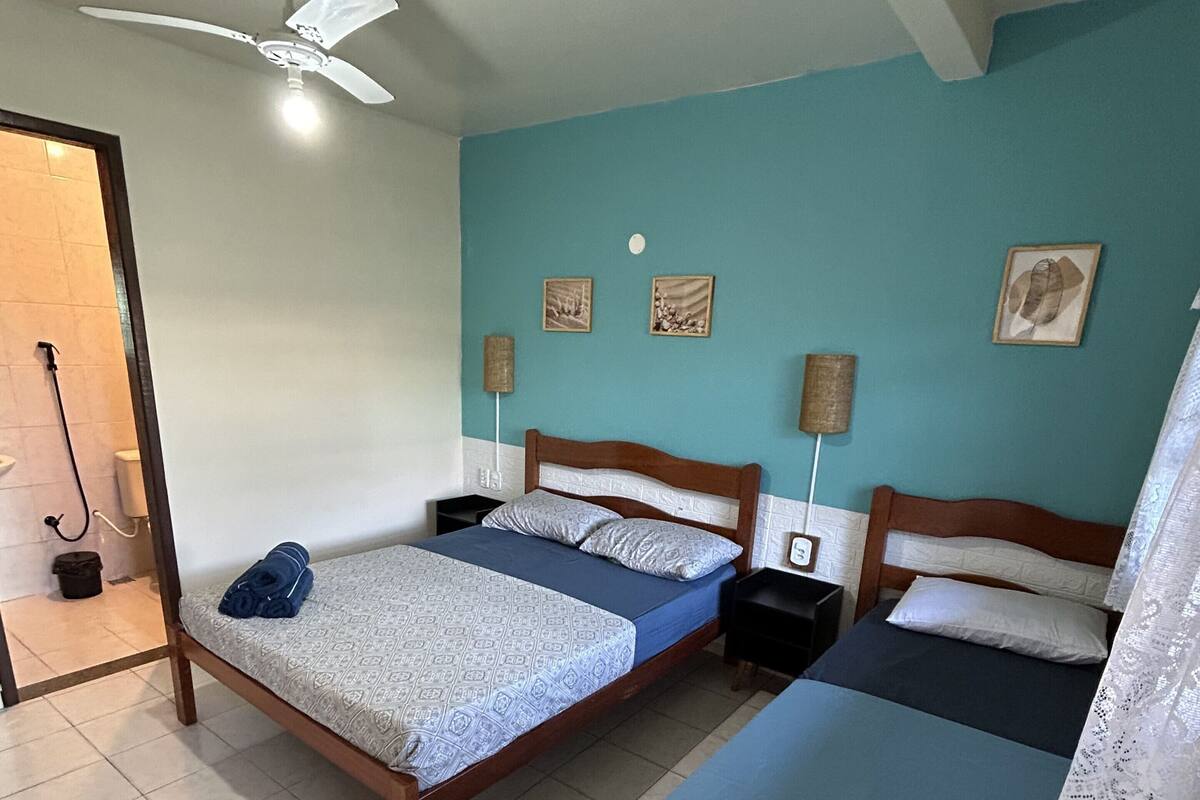 A room with two single beds, a ceiling fan, and a tiled floor.