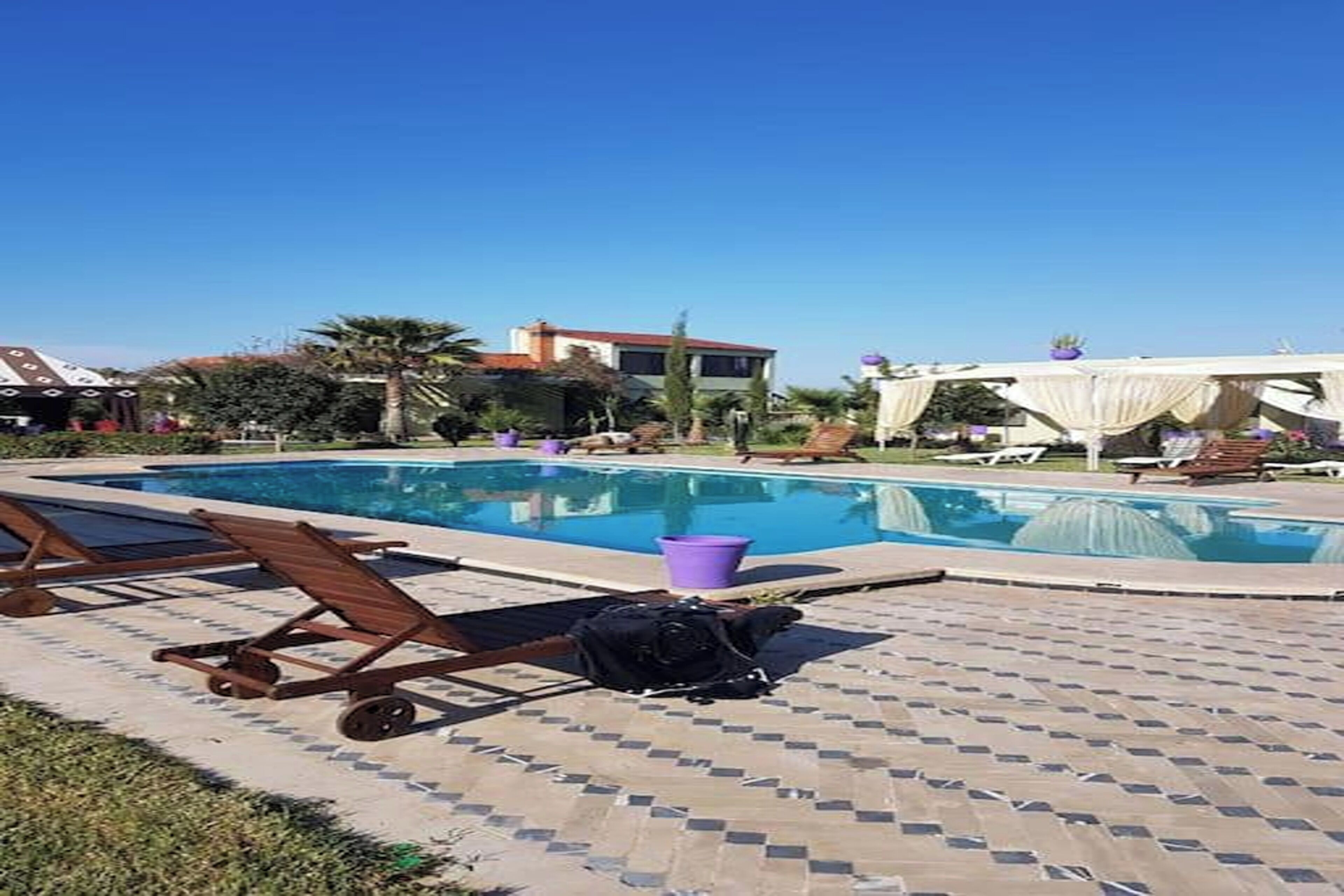 A swimming pool area with lounge chairs and a covered seating area.