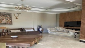 A spacious living room with a large wooden coffee table, two sofas, a television, and a chandelier. - Locanda Villa Marrakech Ourika Road (Ghmate)