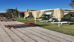A poolside area with sun loungers and a covered seating area. - Locanda Villa Marrakech Ourika Road (Ghmate)