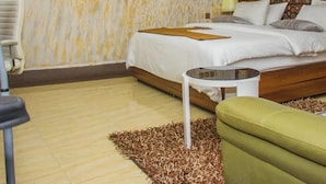 Un dormitorio con una cama, una mesita, una silla verde y un cuadro en la pared.