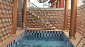 Una piscina con un diseño de baldosas a cuadros, rodeada de muros con patrón de ladrillo.