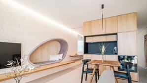 Una cocina moderna con electrodomésticos integrados, un comedor con mesa y sillas de madera y una original zona de estar curva con vistas.