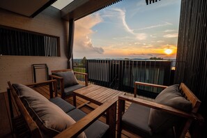 A wooden deck with a table and chairs, a view of the sunset, and a railing. - Stock & Stein Lodges (Bad Gleichenberg)