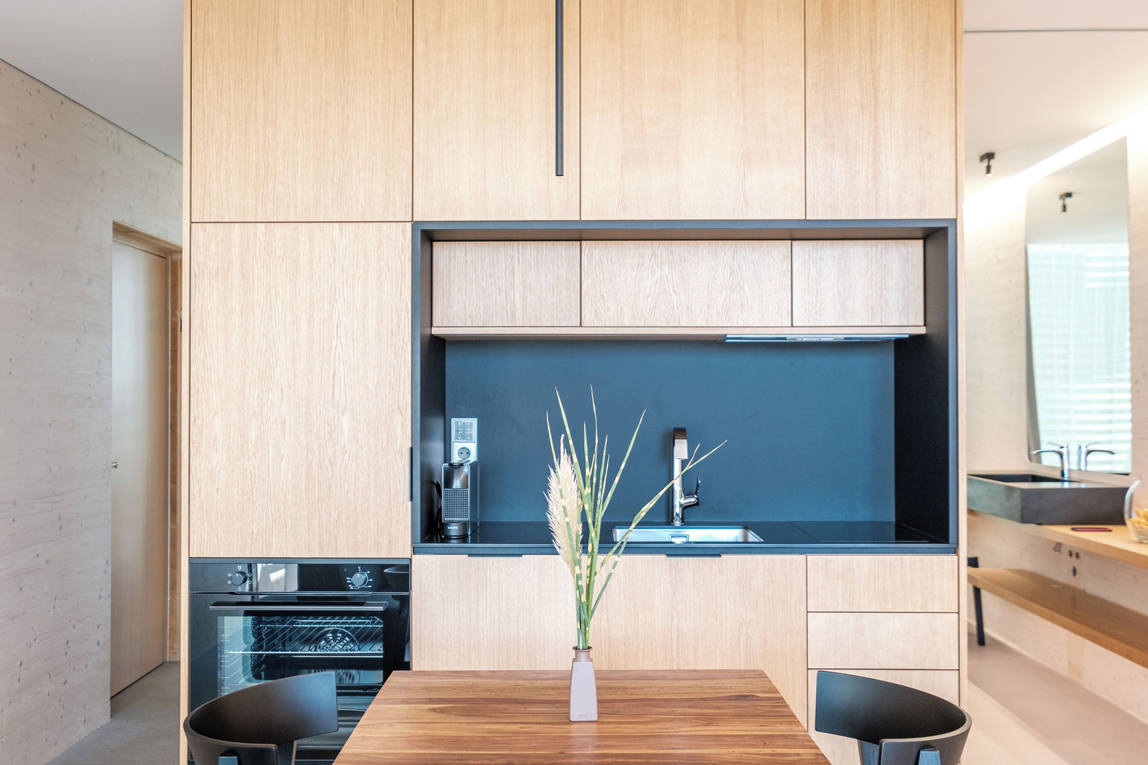 Eine moderne Küche mit Holzausstattung, Backofen und schwarzer Arbeitsplatte.