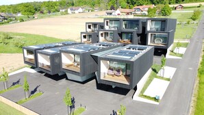 Un moderno complejo residencial con varias unidades, balcones, paneles solares y un patio central.