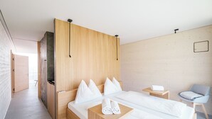 Una habitación de hotel moderna con dos camas, un cabecero de madera, una mesita con toallas y una silla.
