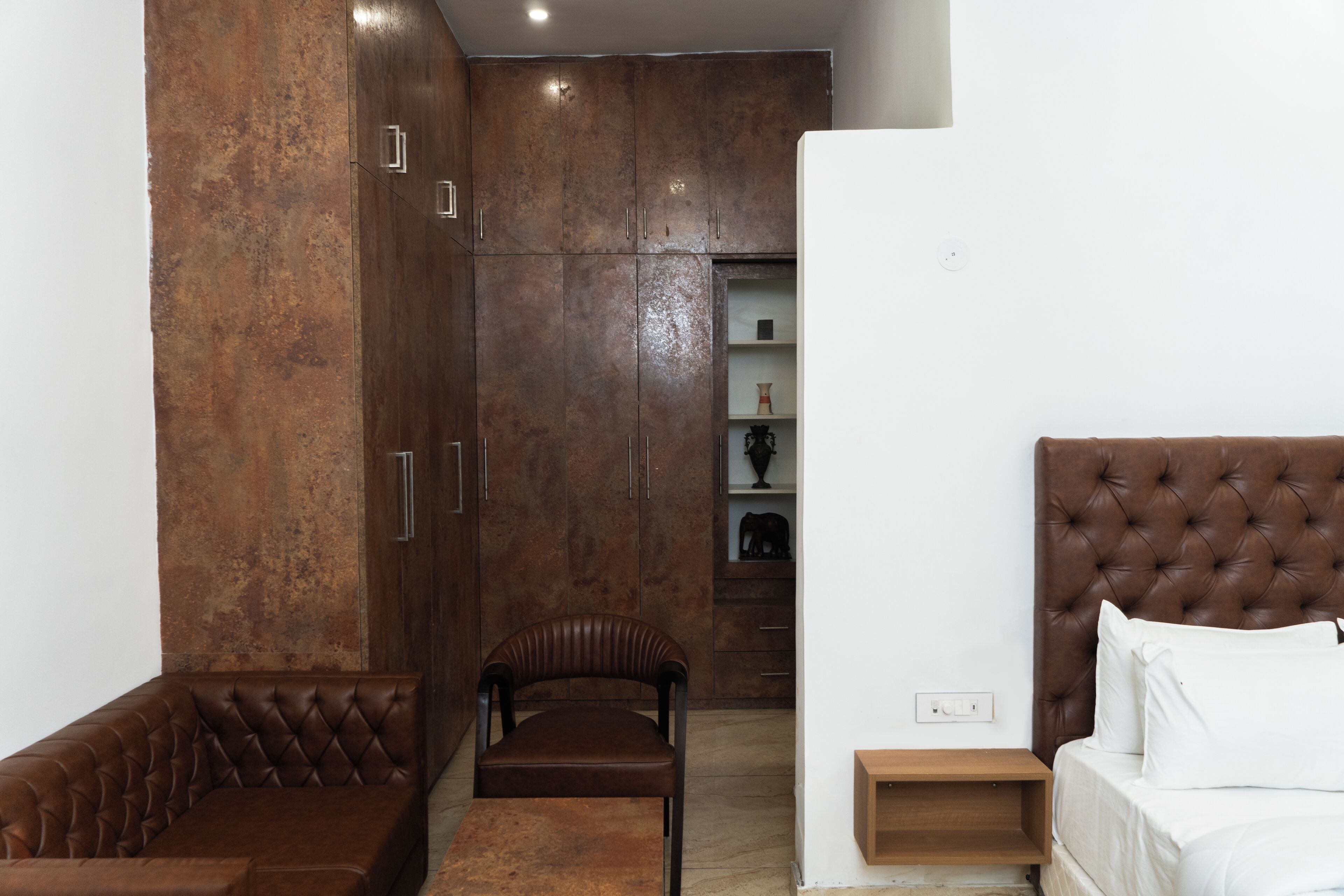 Un dormitorio con cama, silla, armario y mesita de noche.