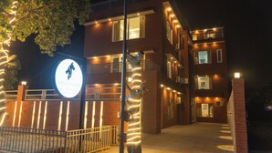 A multi-story building with a well-lit entrance, a visible sign, and a gated driveway. - Sandane Homes India Expo Centre & Mart (Greater Noida)