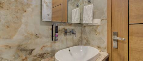 A bathroom with a marble wall, a white sink, and a wooden door.
