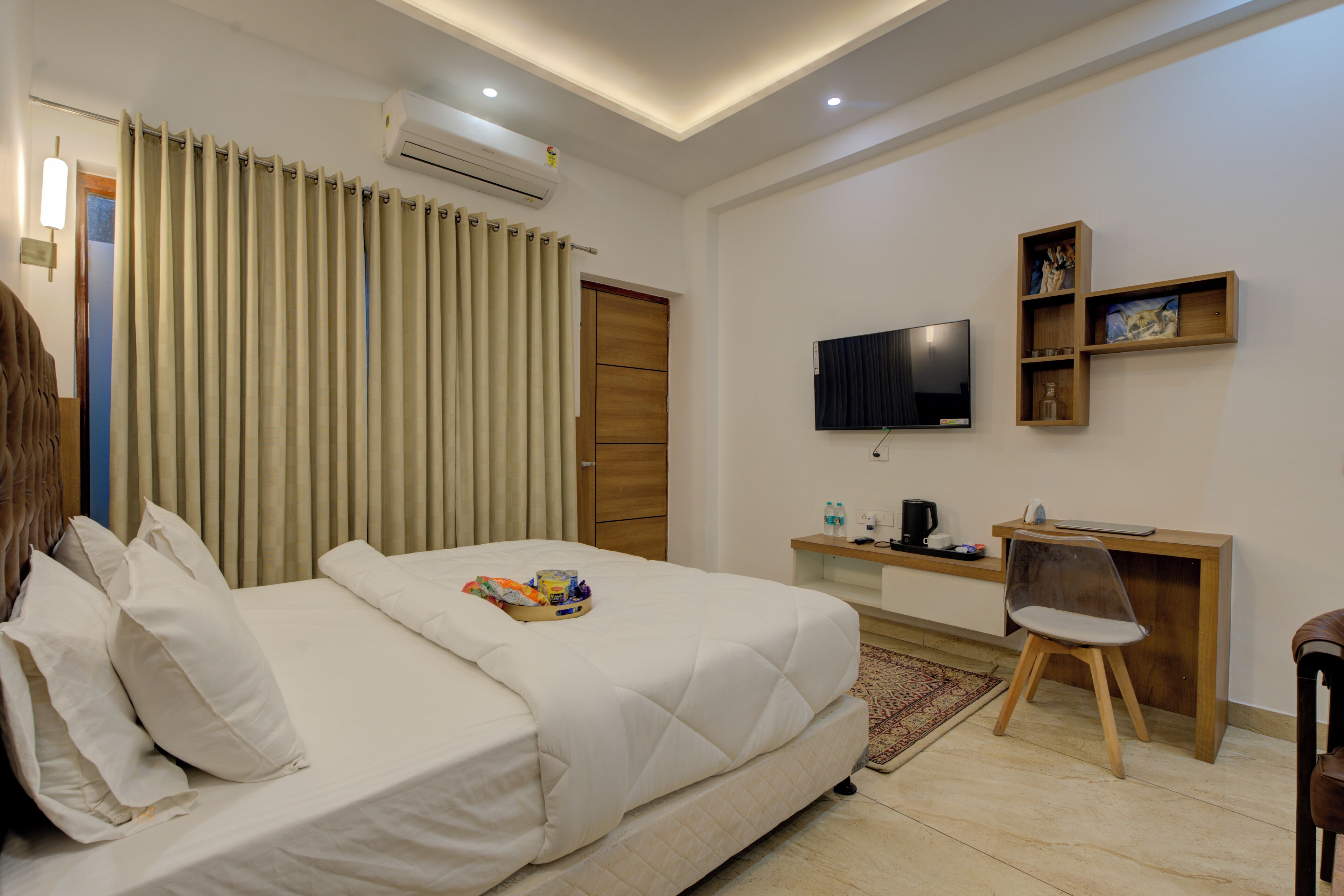 Ein Hotelzimmer mit Bett, Schreibtisch, Stuhl, Fernseher und einem Regal mit Dekoration.