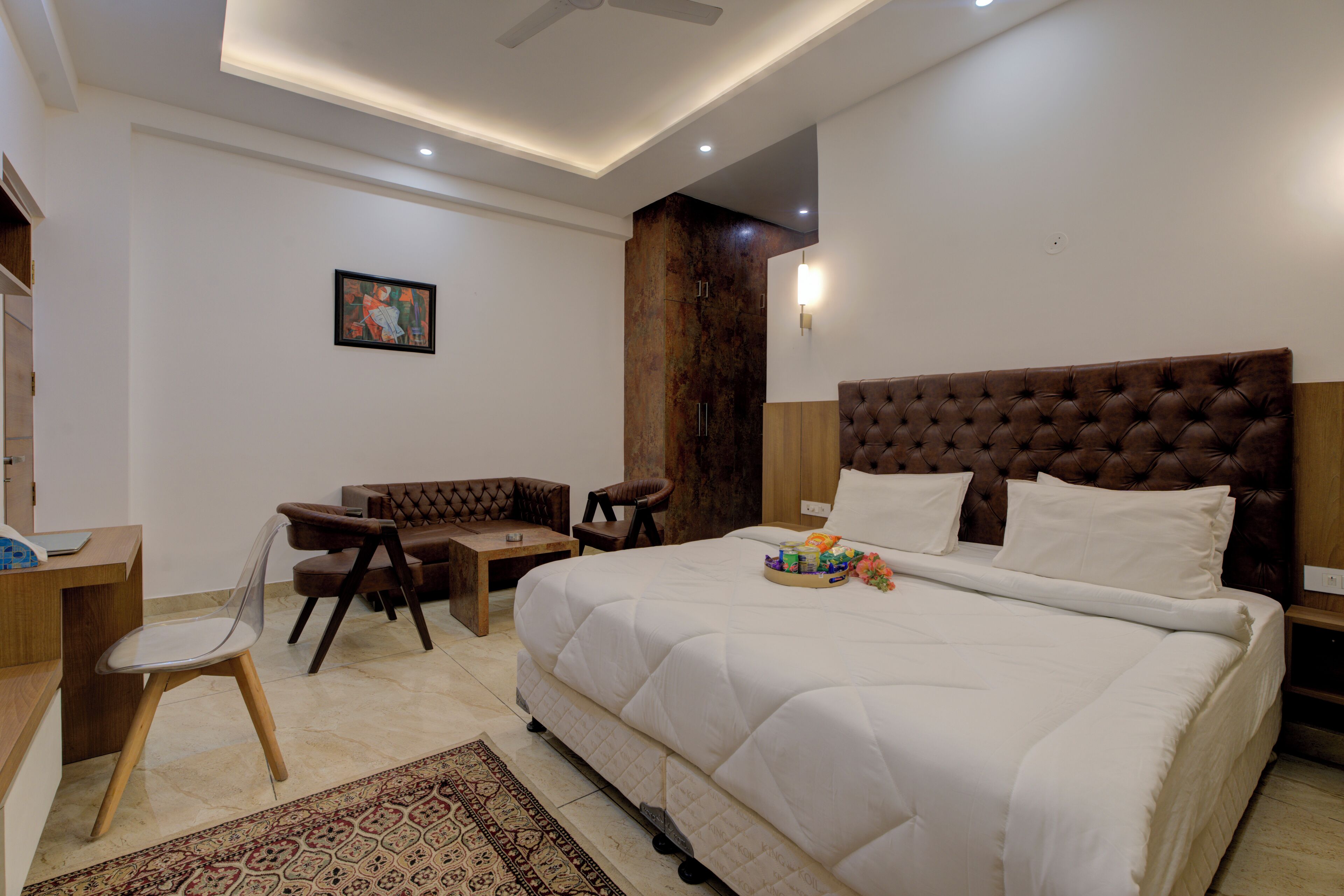 A modern bedroom with a large bed, a desk, and a chair.
