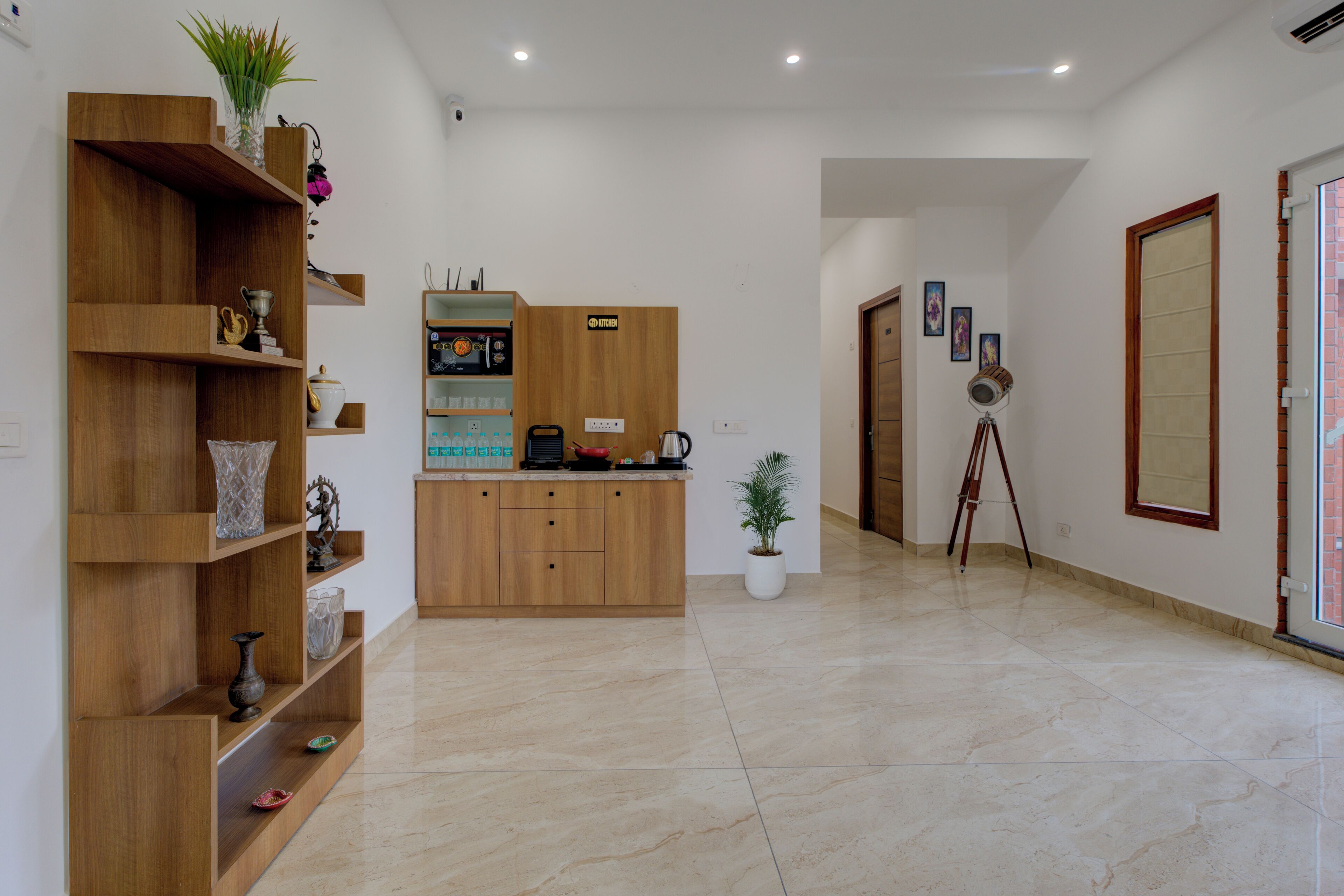 A spacious, well-lit hotel lobby with a wooden reception desk, a potted plant, and a tripod in the background.