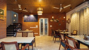 A restaurant interior with wooden ceiling, brick walls, and multiple dining tables and chairs. - Sandane Homes India Expo Centre & Mart (Greater Noida)