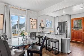A modern kitchen with a central island, stainless steel appliances, and a wooden door.