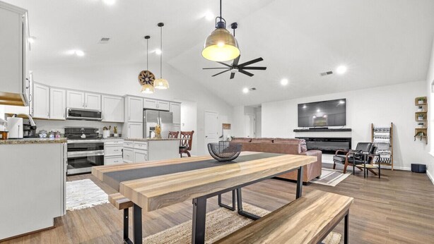 A spacious living area with a wooden dining table, a sofa, and a TV.