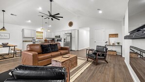 A modern kitchen with white cabinets, stainless steel appliances, and a ceiling fan.
