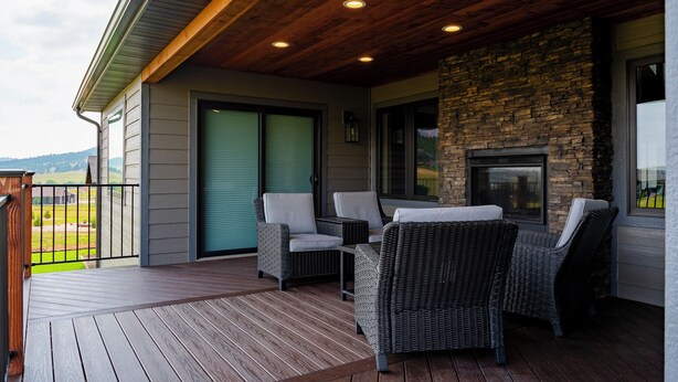 Une terrasse couverte, aménagée avec des meubles en osier et dotée d’une cheminée en pierre.