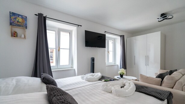 A hotel room with two beds, a TV, a wardrobe, and a window with curtains.