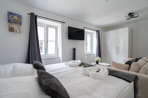 A hotel room with two beds, a TV, a wardrobe, and a window with curtains. - Wachau Oasis | 45m² | Stylish with terrace | For 4 people | WLAN & washer-dryer (Mautern an der Donau)