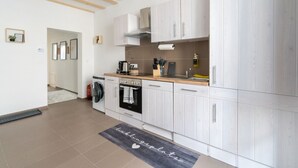 A modern kitchen with white cabinetry, a wooden countertop, and a built-in oven.