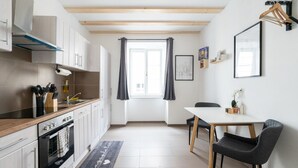 A modern kitchen with a wooden countertop, white cabinets, and a dining area with a table and chairs.