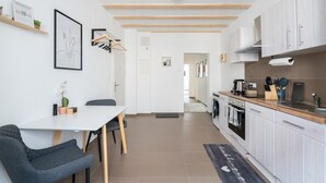 A modern kitchen with white cabinets, a wooden ceiling, and a dining area with a table and chairs.