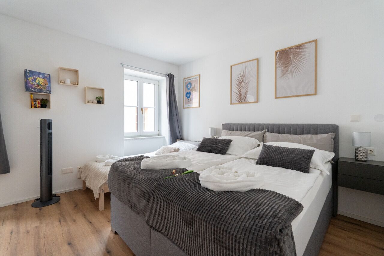 Une chambre à coucher avec un lit, une table de chevet et une fenêtre.